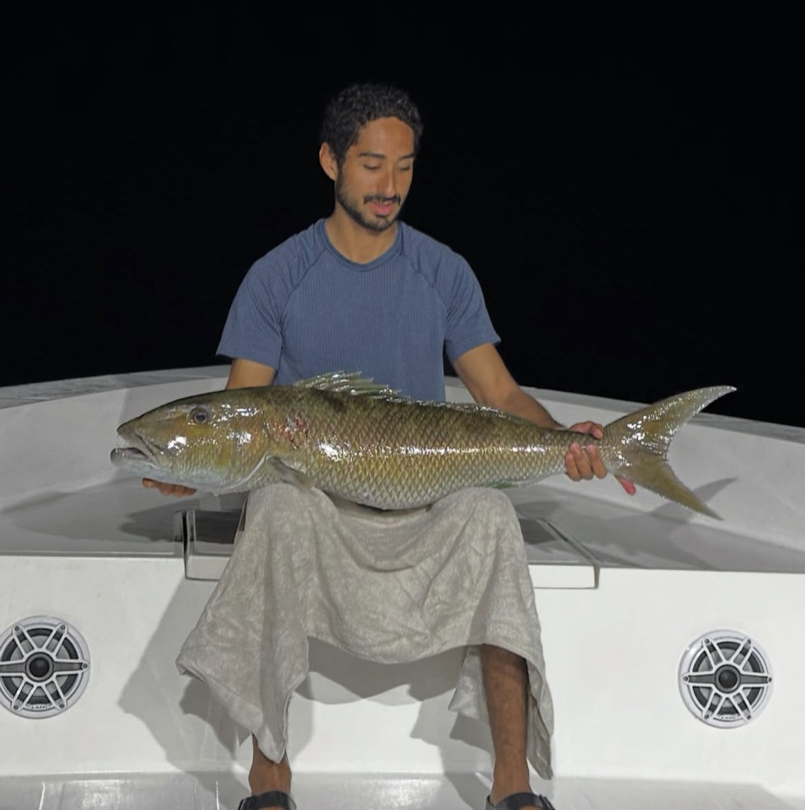 Guest holding a red snapper caught on a night fishing charter in Maldives