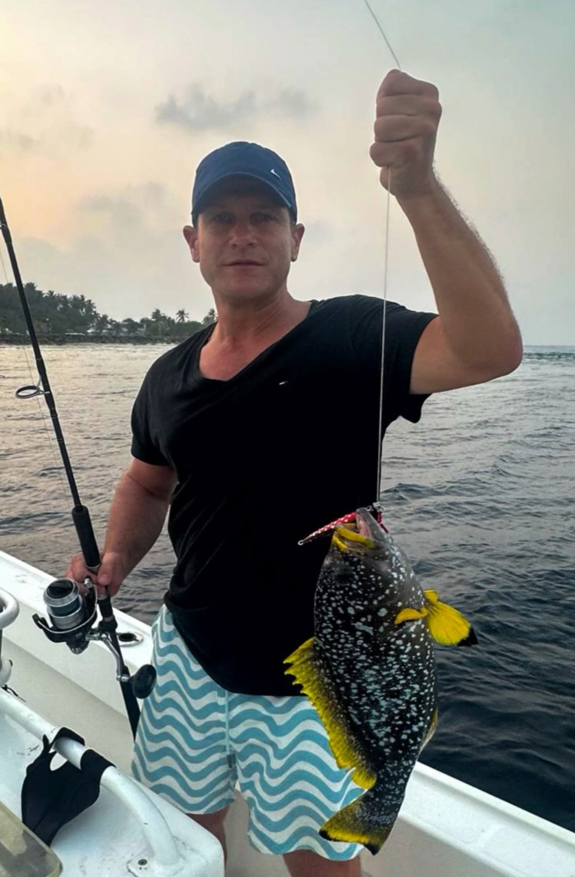 Guest with coral grouper and reef fish caught on a jigging charter