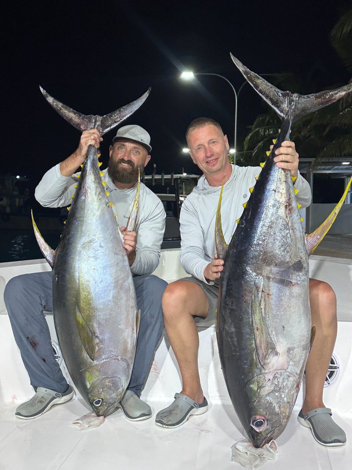 Guests holding yellowfin tuna on night fishing trip