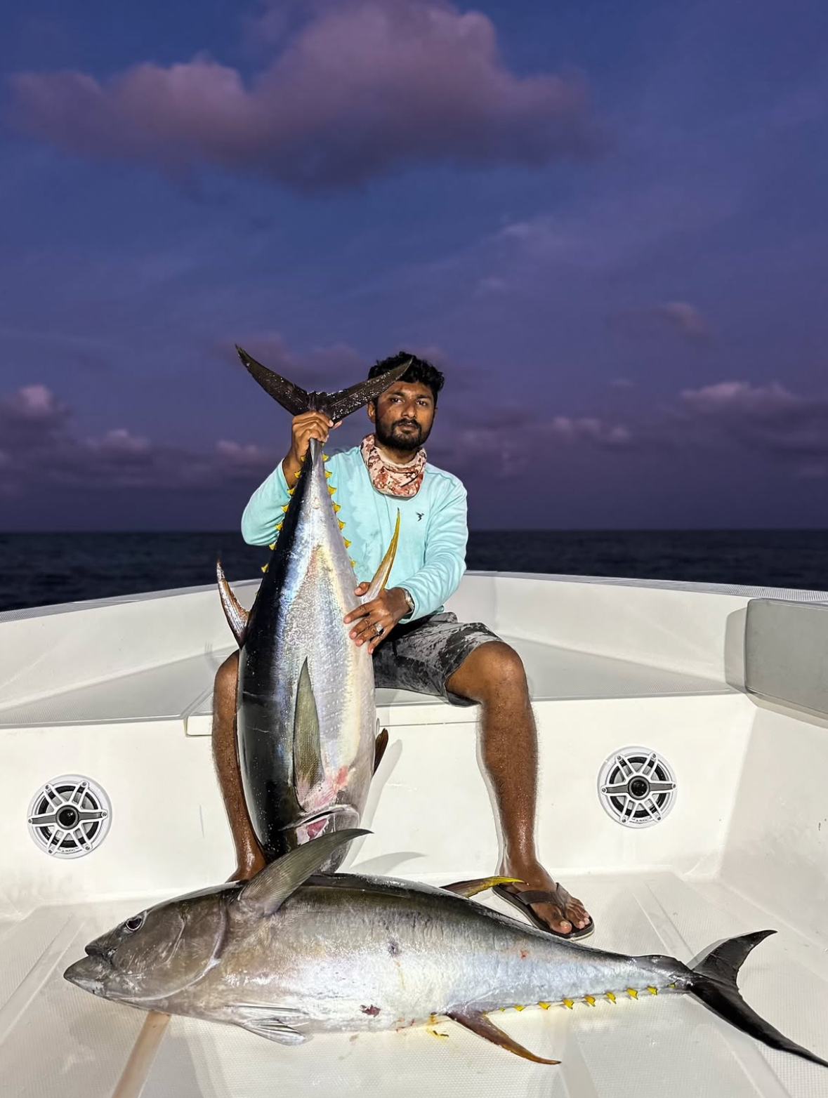 Guests holding two huge yellowfin tuna caught on a night fishing trip